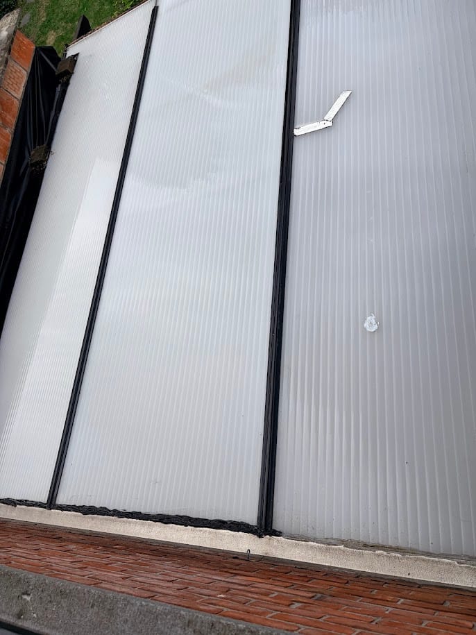 Veranda met polycarbonaat kanaalplaten en zwarte profielen, van bovenaf gezien.