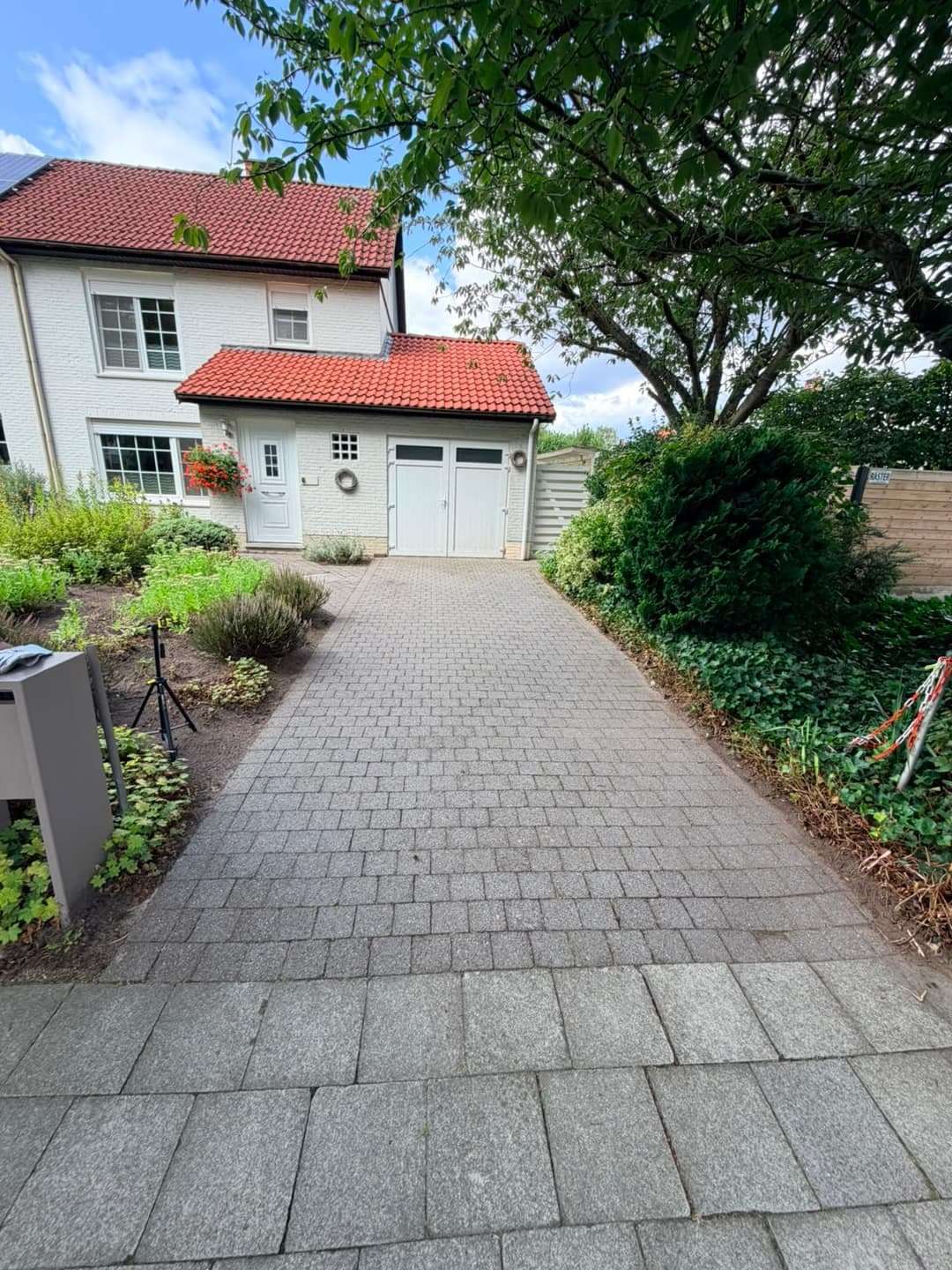 Oprit in betonklinkers met een grauwe, vlekkerige waas en donkere voegen, voor de reiniging.